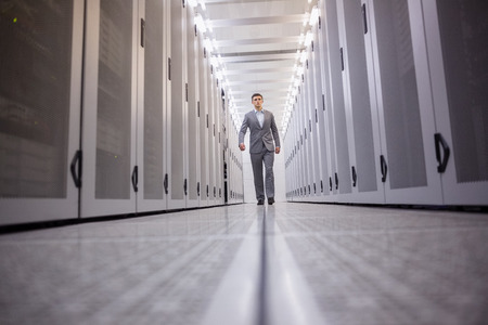 Young technician walking to the camera in a large data center