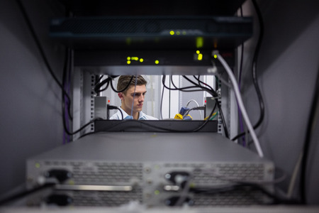 Serious technician using digital cable analyzer on server in large data center