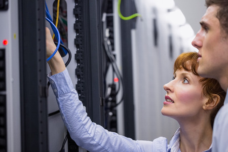 Team of technicians talking and looking at server in large data center