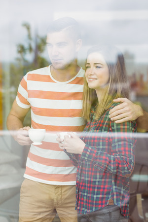 Cute couple looking out the window at home in the kitchenの写真素材