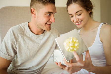 Cute girlfriend opening her gift at home in the bedroom