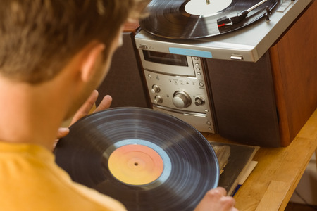 Young man looking at his vinyl collection at home in the living room