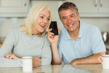 Mature couple on a phone call together at home in the kitchenの写真素材