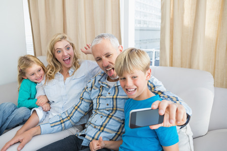 Happy family taking a selfie on couch at home in the living room