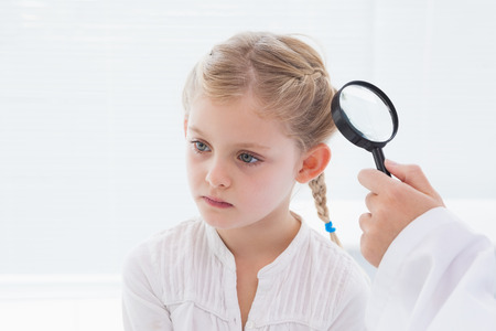 Doctor examining patient with magnifying glass in medical officeの写真素材