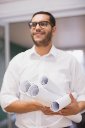 Casual architect holding his blueprints in the officeの写真素材