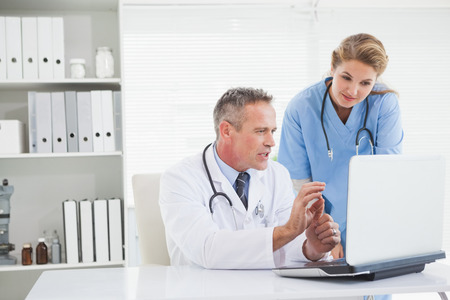 Doctor and nurse looking at laptop in medical officeの写真素材