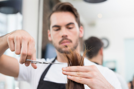Handsome hair stylist cutting hair at the hair salonの写真素材