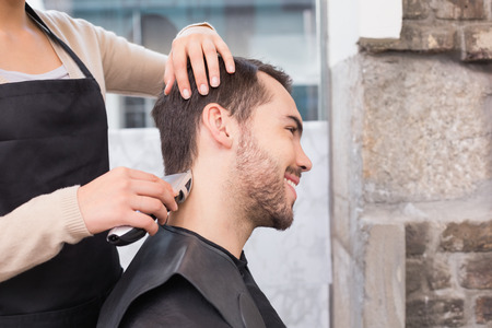 Handsome man getting his hair trimmed at the hair salonの写真素材