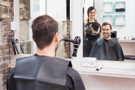 Pretty hair stylist showing man new haircut at the hair salonの写真素材