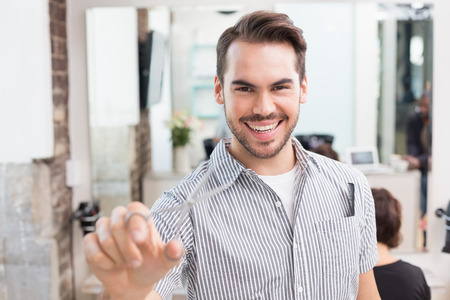 Handsome hair stylist holding scissors at the hair salonの写真素材