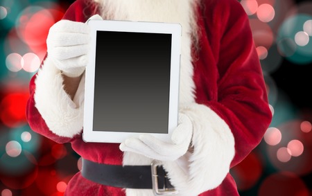 Santa claus showing tablet pc against digitally generated twinkling light design の写真素材
