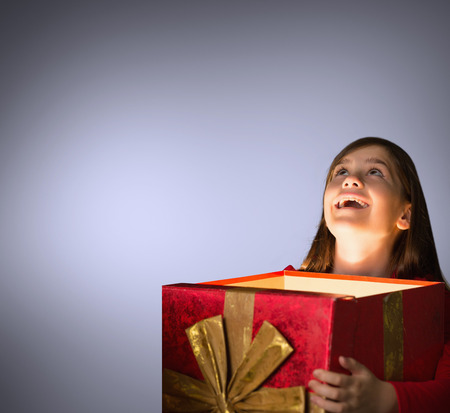 Happy girl opening gift box against grey vignette