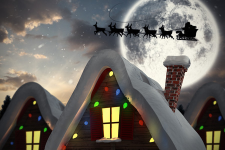 Silhouette of santa and reindeer against cute christmas village under full moonの写真素材