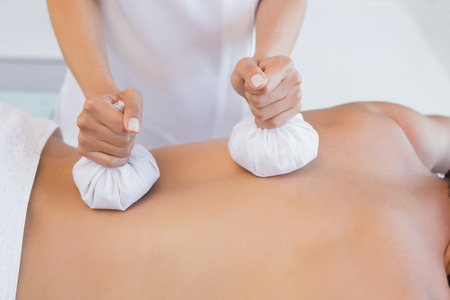Close up mid section of a man receiving back massage at spa centerの写真素材