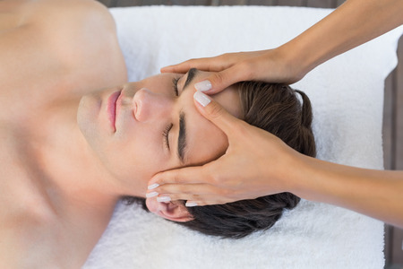Close up of a handsome young man receiving head massage at spa centerの写真素材