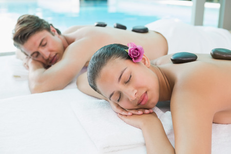 Side view of a young couple enjoying stone massage at health farmの写真素材