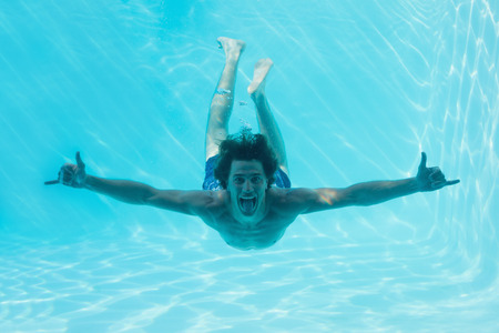 Full length portrait of a young man swimming underwaterの写真素材