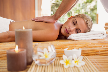 Attractive young woman receiving back massage at spa centerの写真素材