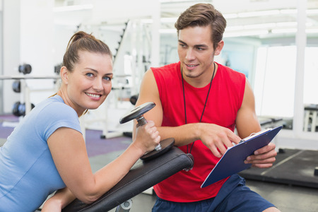 Personal trainer working with client holding dumbbell at the gym