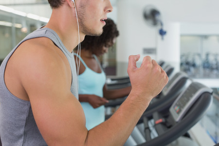 Fit man and woman running on treadmill at the gym