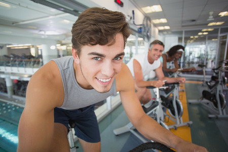 Three fit people working out on exercise bikes at the gymの写真素材