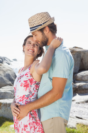 Gorgeous couple embracing by the coast on a sunny dayの写真素材