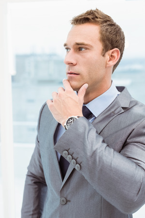 Close up of thoughtful young businessman looking away at officeの写真素材