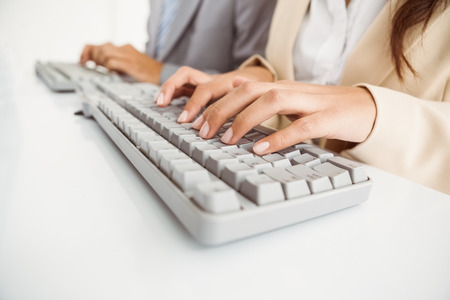 Close-up side view of business people using computers in officeの写真素材
