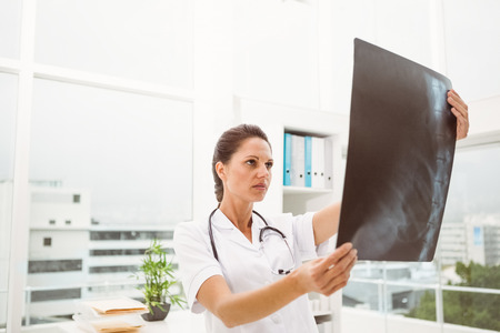 Serious female doctor examining x-ray in the medical office