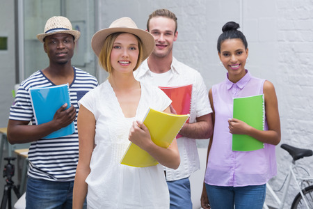 Portrait of young creative business people holding files in the office