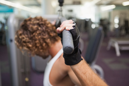 Side view of a young man exercising on a lat machine in gymの写真素材