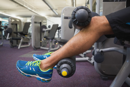 Side view low section of a man doing leg workout at the gym
