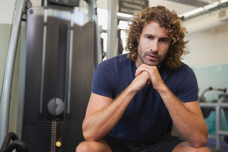 Portrait of a serious handsome trainer sitting in the gymの写真素材