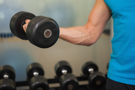 Close up mid section of man exercising with dumbbell in the gymの写真素材