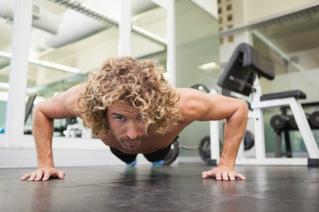 Portrait of a handsome young man doing push ups in the gym