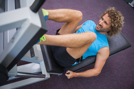 High angle view of young handsome man doing leg presses in the gym