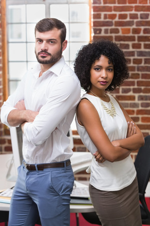 Portrait of two confident young business people with arms crossed in officeの写真素材