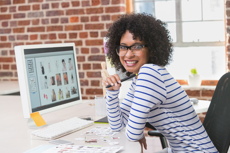 Portrait of smiling female photo editor sitting at office deskの写真素材