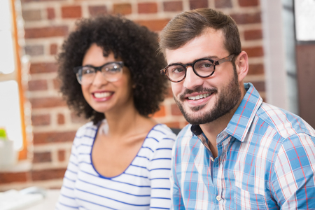 Portrait of two confident young business people smiling in officeの写真素材
