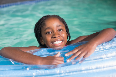 Cute little girl swimming in the pool at the leisure centerの写真素材