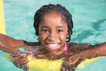Cute little girl swimming in the pool at the leisure centerの写真素材