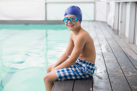Cute little boy sitting poolside at the leisure centerの写真素材