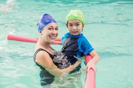 Cute little boy learning to swim with coach at the leisure centerの写真素材