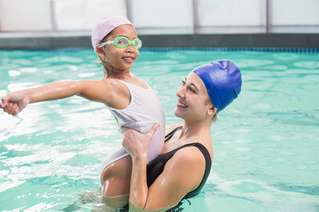 Happy mother and daughter in the swimming pool at the leisure centerの写真素材