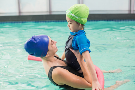 Cute little boy learning to swim with coach at the leisure centerの写真素材