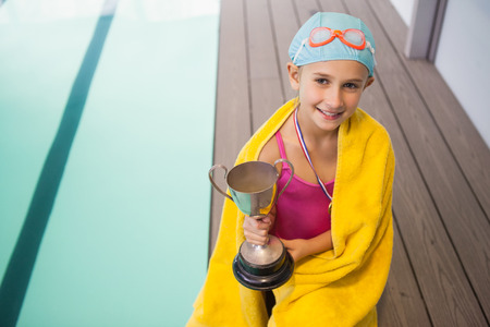 Cute little girl sitting poolside wrapped in towel at the leisure centerの写真素材