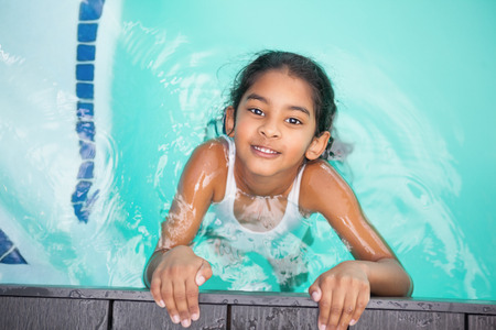 Cute little girl smiling in the pool at the leisure centerの写真素材