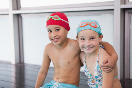Cute little kids sitting poolside at the leisure centerの写真素材