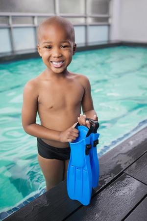 Little boy holding flippers by the pool at the leisure centerの写真素材